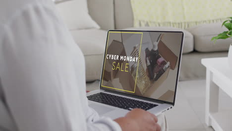 una mujer biracial usando una computadora portátil en casa para comprar en línea en cyber monday, en cámara lenta
