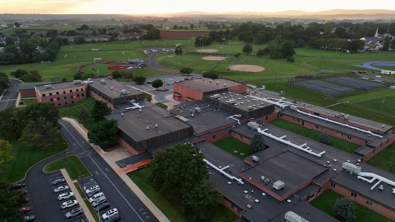 Ephrata Senior High School with parking cars in summer season. Aerial approaching shot. Sport area with baseball fields in background. Aerial rising Wide shot. Ephrata, Pennsylvania