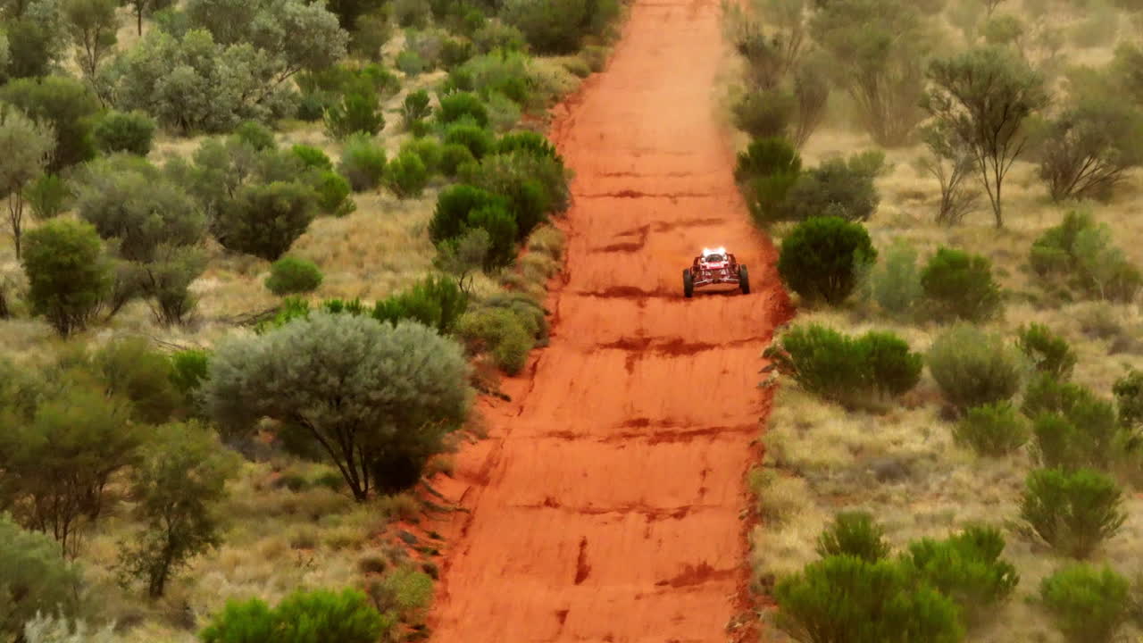 carreras de buggy de cuatro ruedas sobre una pista rural de tierra roja accidentada en el interior del bosque australiano, dron de teleobjetivo 4k