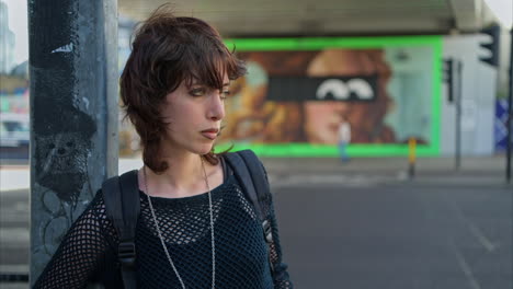 retrato de moda al aire libre de una mujer joven de estilo alternativo de pie en la calle de la ciudad de londres, reino unido, con una carretera ocupada en el fondo 3