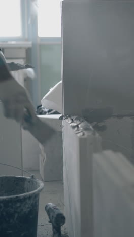 professional repair worker holds big putty knife and smears large gypsum plasterboard walls close view