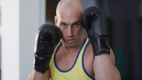 portrait of caucasian male trainer wearing boxing gloves training at the gym