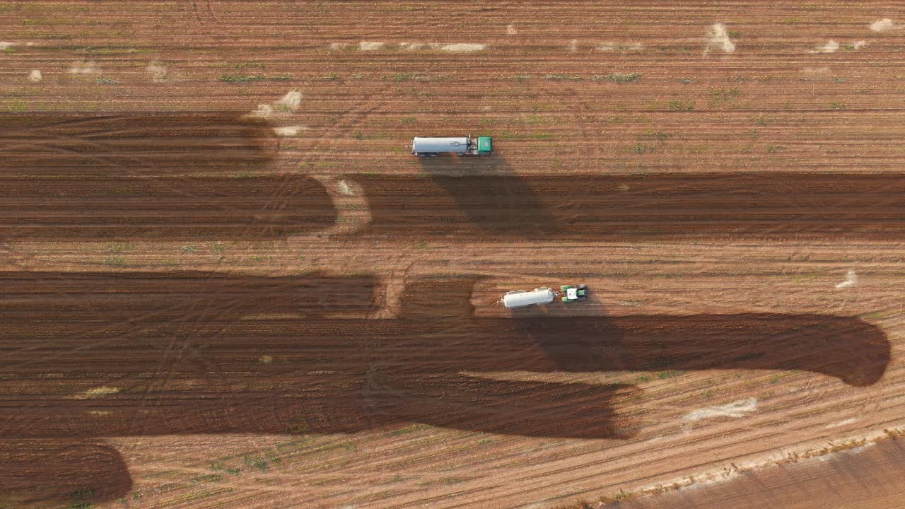 Agricultural Farm tractors spraying liquid Manure over ploughed fields