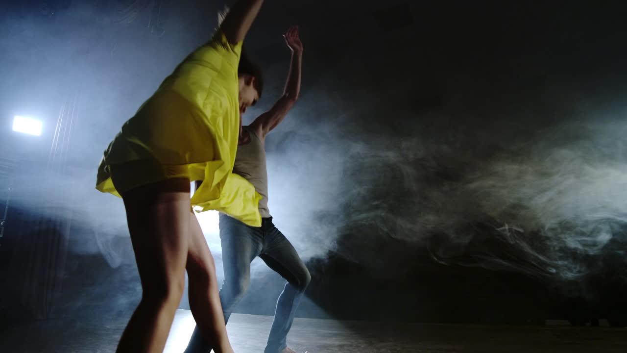 Zoom camera a female dancer jumps onto her partner shoulder. Acrobatic dance musical on stage in smoke. Contemporary