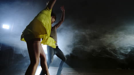 zoom camera a female dancer jumps onto her partner shoulder. acrobatic dance musical on stage in smoke. contemporary