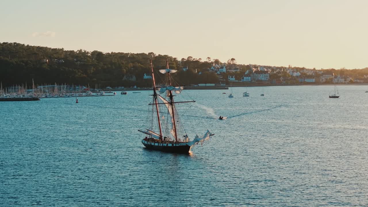 Ripresa con drone di un motoscafo che si avvicina a una nave a vela ancorata nella Baia di Crozon, Francia.