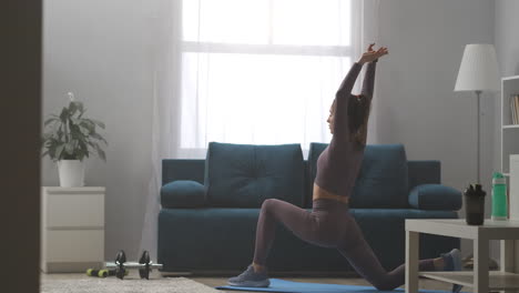 Práctica-De-Yoga-En-Casa-Joven-Deportista-Está-Entrenando-Sola-En-La-Sala-De-Estar-Durante-El-Fin-De-Semana-Realizando-Pose-De-Guerrero-Estirándose-En-Asana