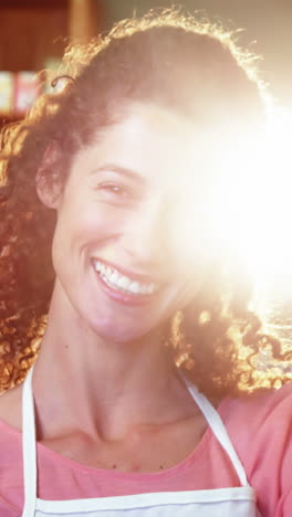 personal femenino sonriente de pie con las manos en la cadera en la sección de comestibles