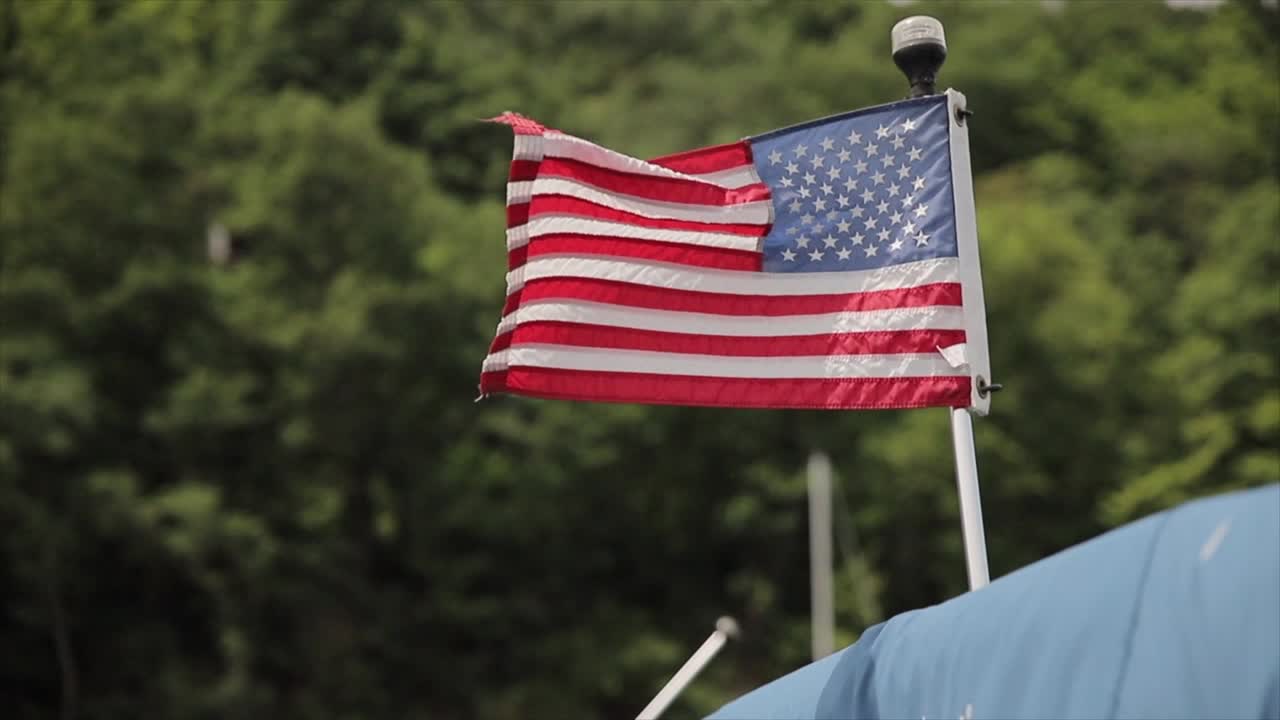 una bandera estadounidense ondeando en el viento montada en una luz de poste de navegación en todas partes en un barco