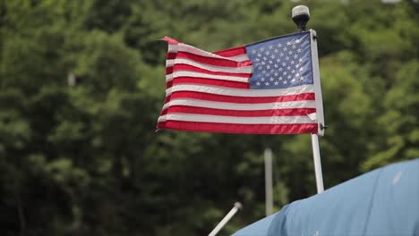 an american flag waving in the wind mounted to a all-round navigation pole light on a boat