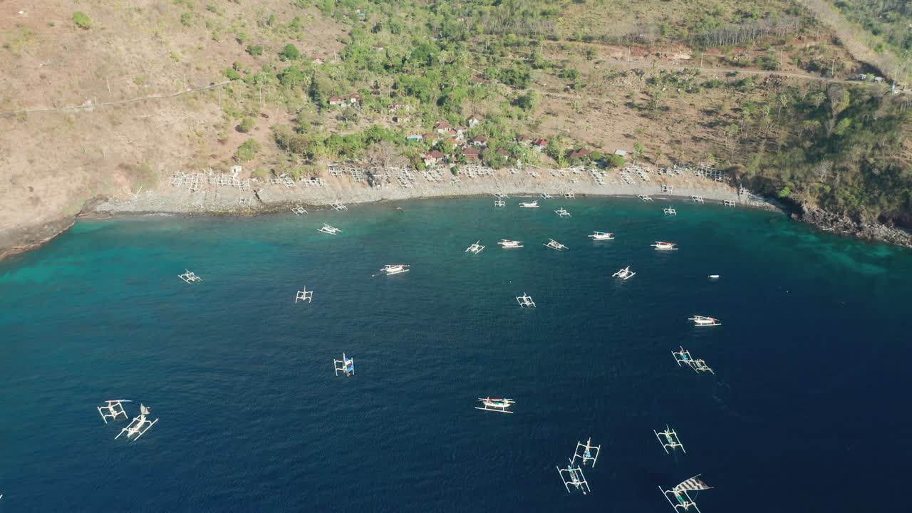 Tropical blue water at Bali shore with traditional Jukung outrigger boats floating