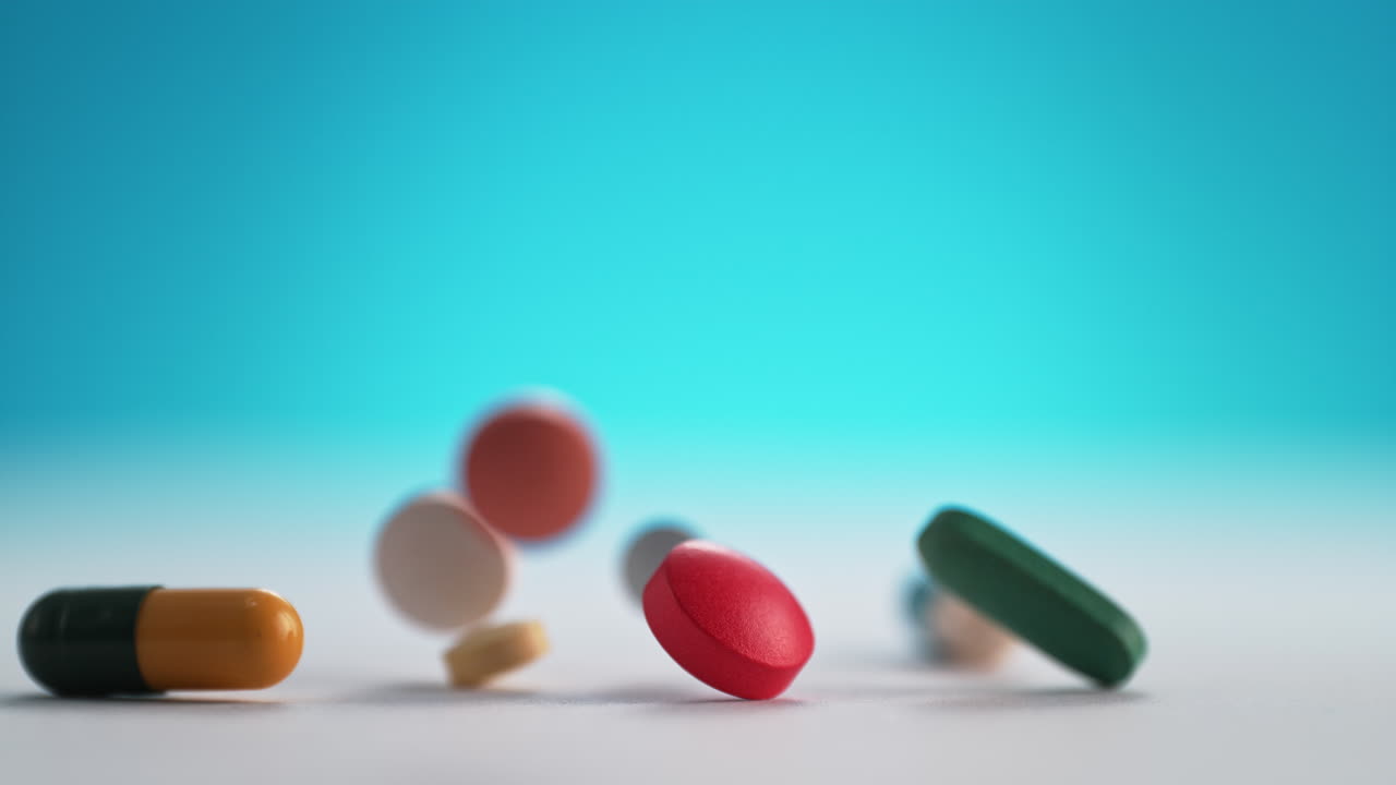 pastillas y pastillas de colores caen sobre una mesa blanca y rebotan en cámara lenta y macro en el fondo azul
