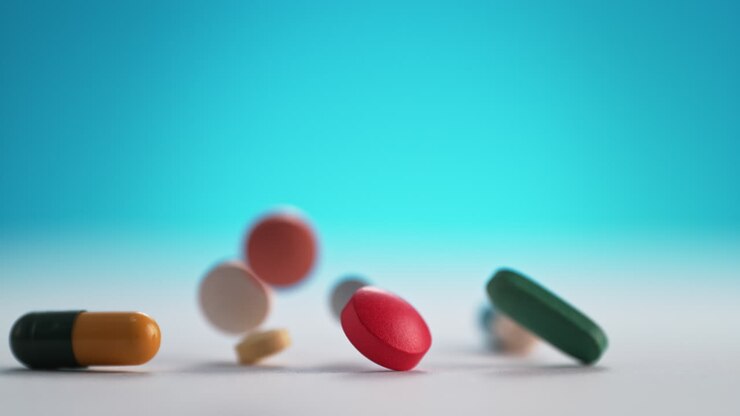 pastillas y pastillas de colores caen sobre una mesa blanca y rebotan en cámara lenta y macro en el fondo azul