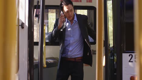 business commuter talking on mobile phone while getting out from bus 4k