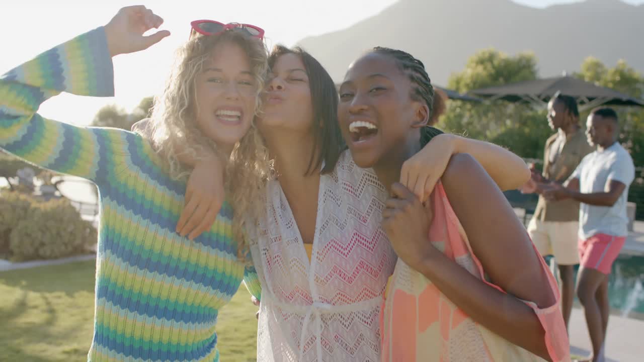 retrato de felices amigas diversas abrazándose y divirtiéndose en una fiesta soleada en la piscina, cámara lenta