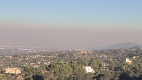 establishing pan across los angeles, thick smoke rising at midday over city skyline after wildfire