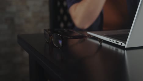 a woman takes her glasses while operating a notebook to finish her office work