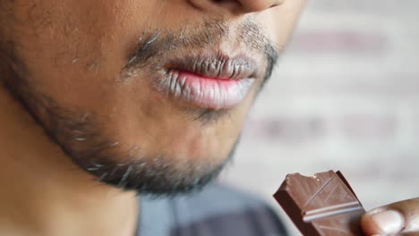 close-up of a man enjoying a piece of dark chocolate