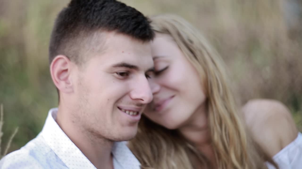 Man And Woman Drinking Wine At A Picnic. Couple sitting on beach and drinking wine from glasses near bonfire in the evening