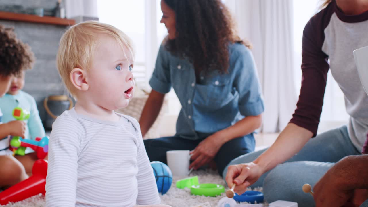 Friends with toddlers playing on the floor in sitting room