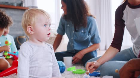 amigos con niños pequeños jugando en el suelo en la sala de estar