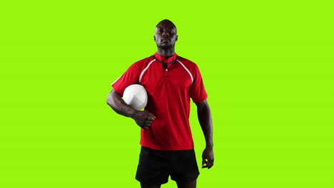 professional rugby player standing and holding a ball on green background 4k