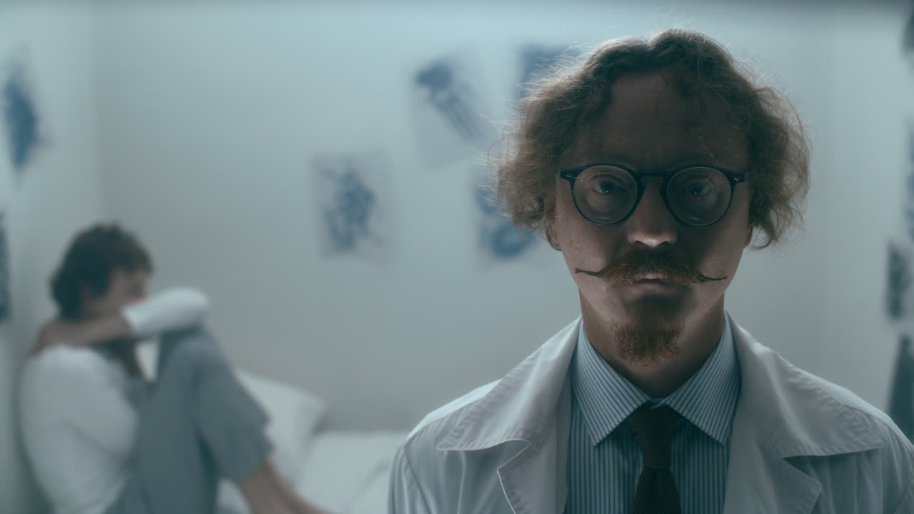 Portrait of Psychiatrist Standing in Ward with Distressed Patient Behind