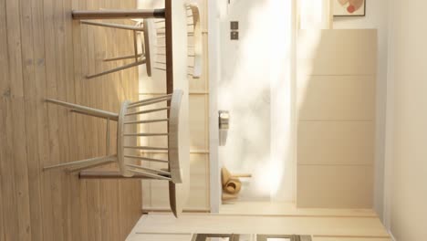 vertical slow-rotating shot of a wooden minimalist kitchen and table in an apartment