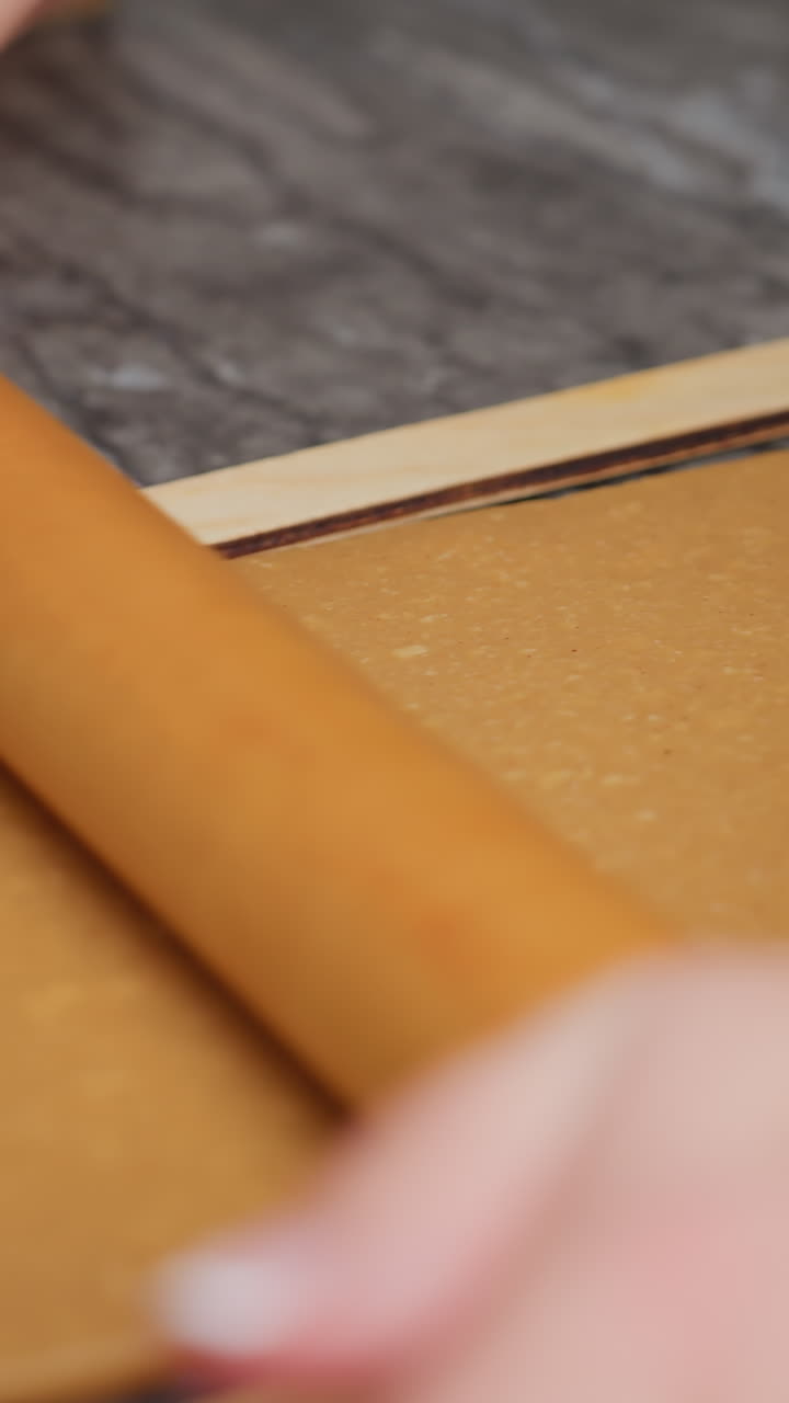 primer plano de las manos de la mujer rodando masa marrón con rodillo de madera, mano izquierda adornada con un brazalete, ligero borrón en el fondo añadiendo profundidad