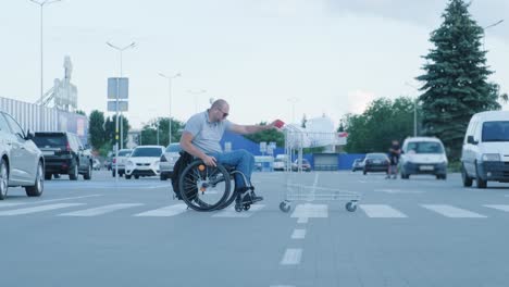 man with disabilities in wheelchair pushing cart in front of himself at supermarket parking