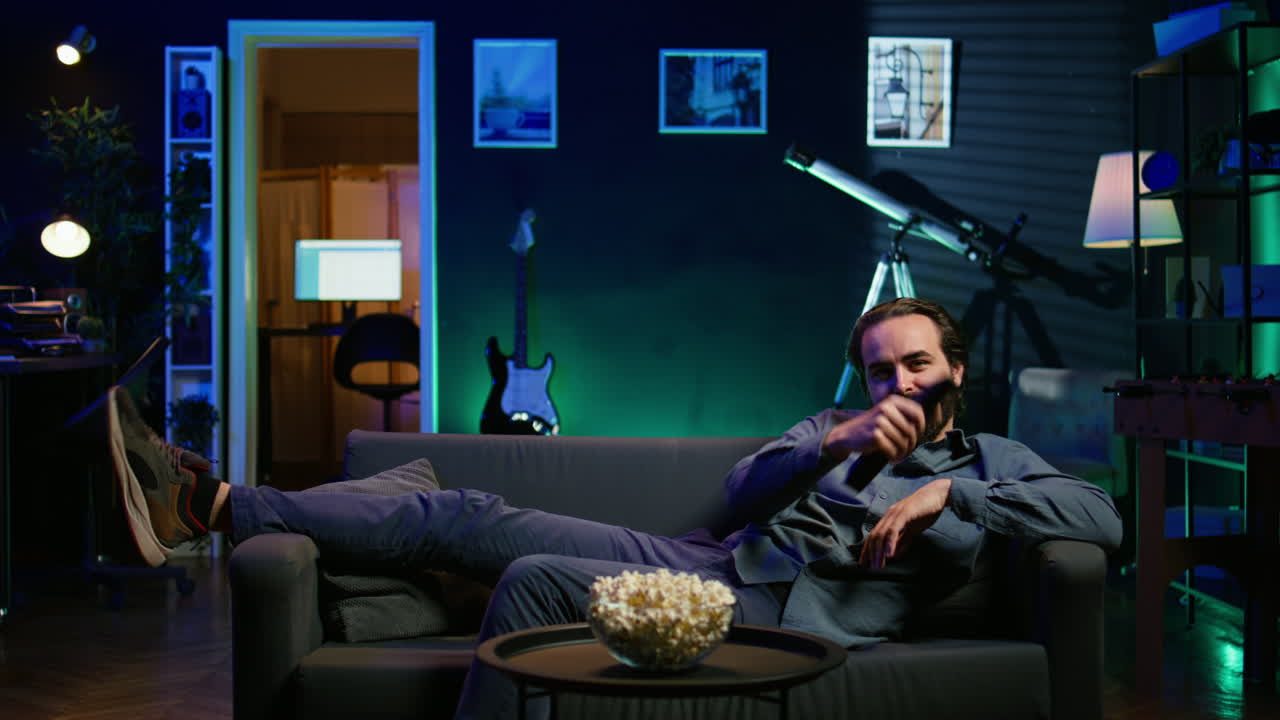 집에서 소파에 뛰어내리는 흥분한 남자, 좋아하는 tv 쇼 에피소드를 보는 데 서두르고