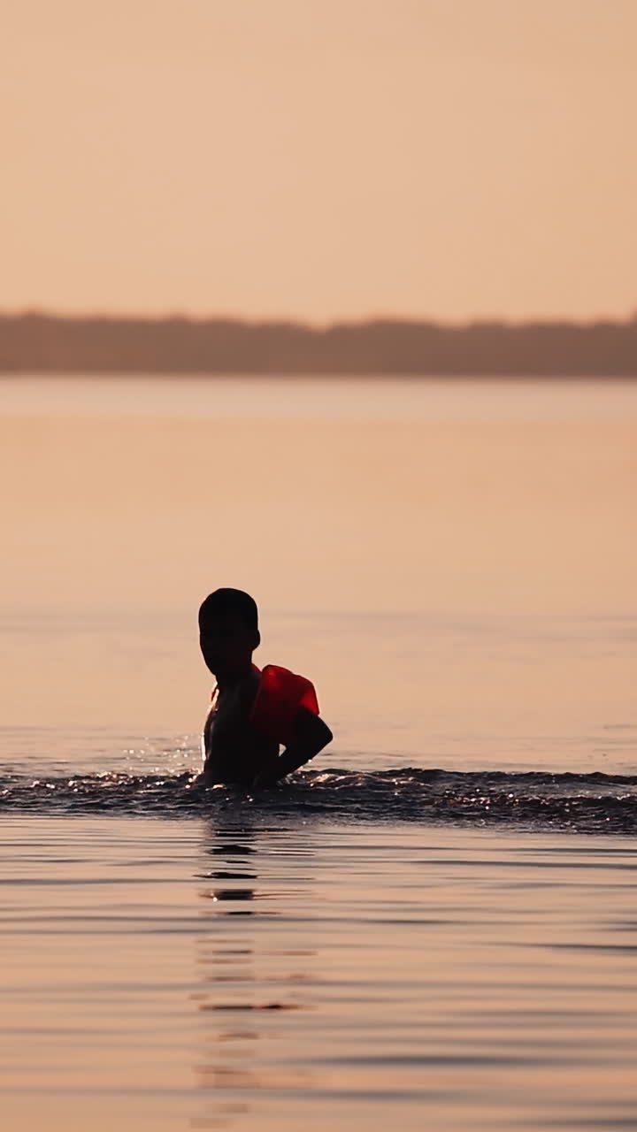 Children playing in water. Little cute boy swimming and splashing with water in the river during vacation Vertical video