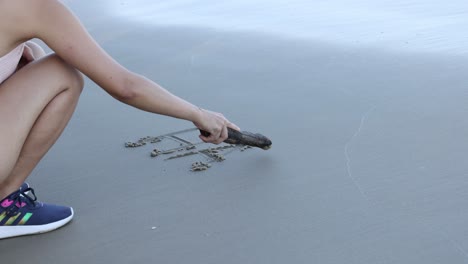 sequential frames of \"happy\"" being written on beach."