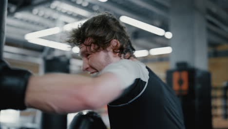 Eager-fighter-working-out-in-fitness-center.-Kickboxer-training-blows-at-gym