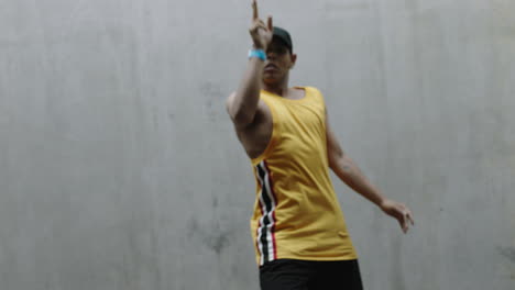 dancing-man-young-happy-street-dancer-performing-various-freestyle-dance-moves-fit-mixed-race-male-practicing-in-grungy-warehouse-wearing-yellow-vest-close-up