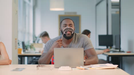 african man working on laptop computer at coworking. joyful man looking camera