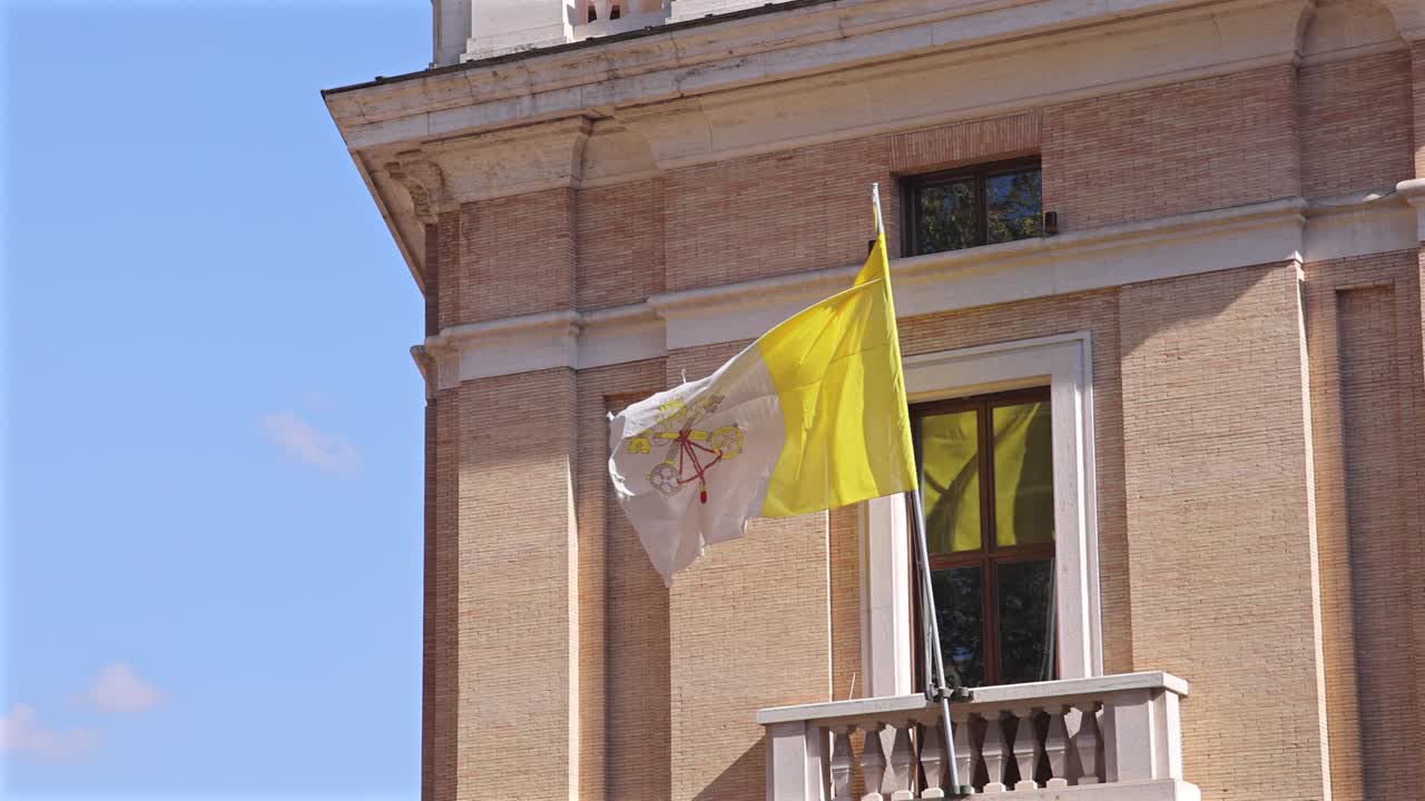 Vatican flag flies prominently outside a classic building on a bright and clear day.