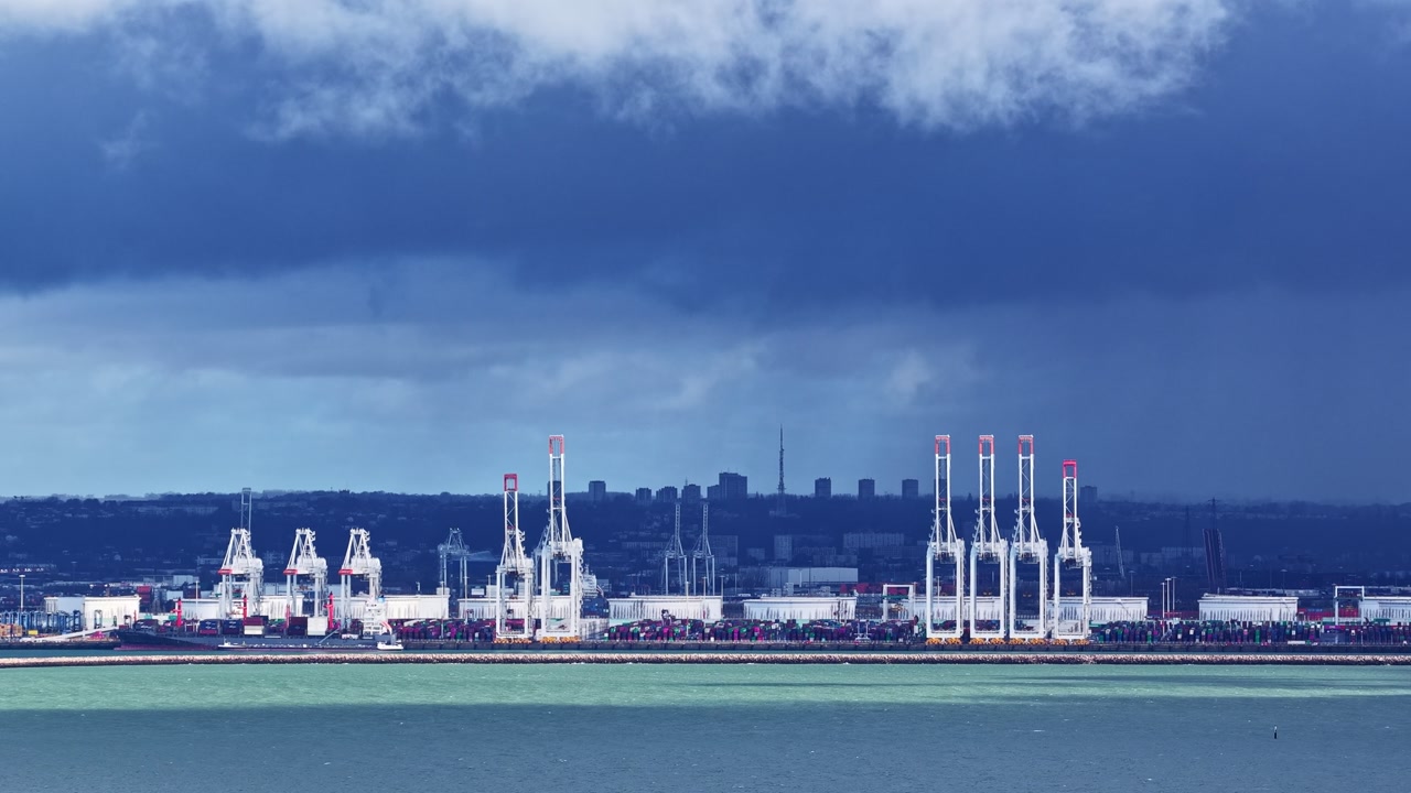 Port containers and shipping cranes on the water at Le Havre, France in aerial timelapse