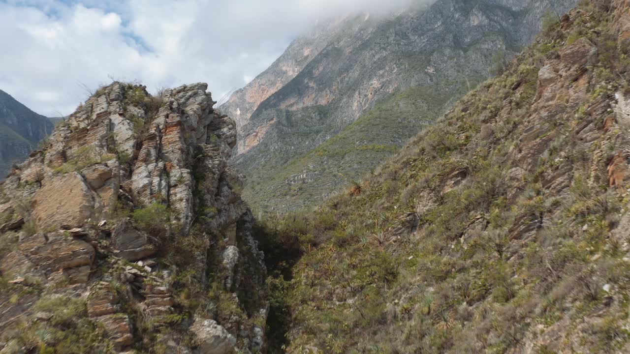 el dron volando a través de la brecha de la montaña da una amplia vista del valle empinado y el terreno escarpado de nuevo león, méxico, cerca de monterrey.