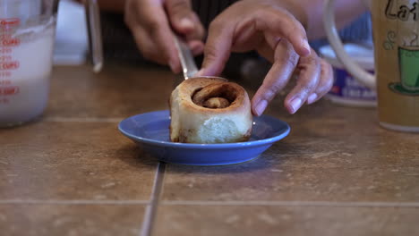 colocar un rollo de canela recién horneado en un plato para glasear y servir - vista lateral en cámara lenta