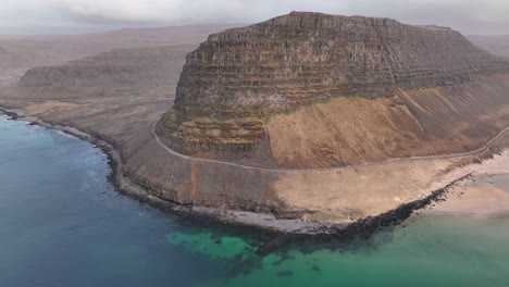 Carretera-Costera-Que-Cruza-El-Borde-De-La-Montaña-Junto-Al-Océano-En-El-Oeste-De-Islandia---Toma-Aérea