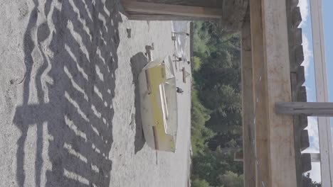 A-yellow-boat-on-the-seashore-beach-surrounded-by-forest-trees-in-Patagonia,-Argentina-with-people-enjoying-recreation-on-vacation