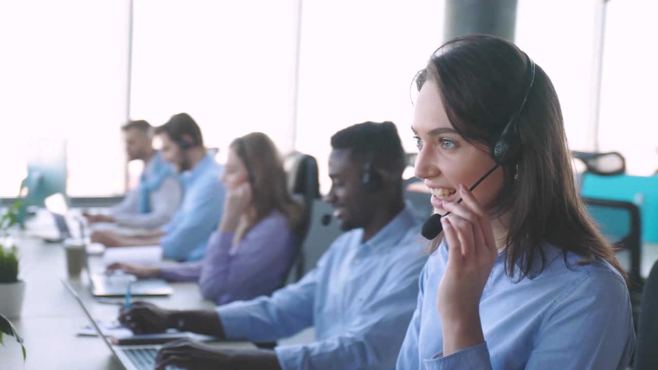 Ung kvinnelig kundekonsulent snakker i headset på kontoret