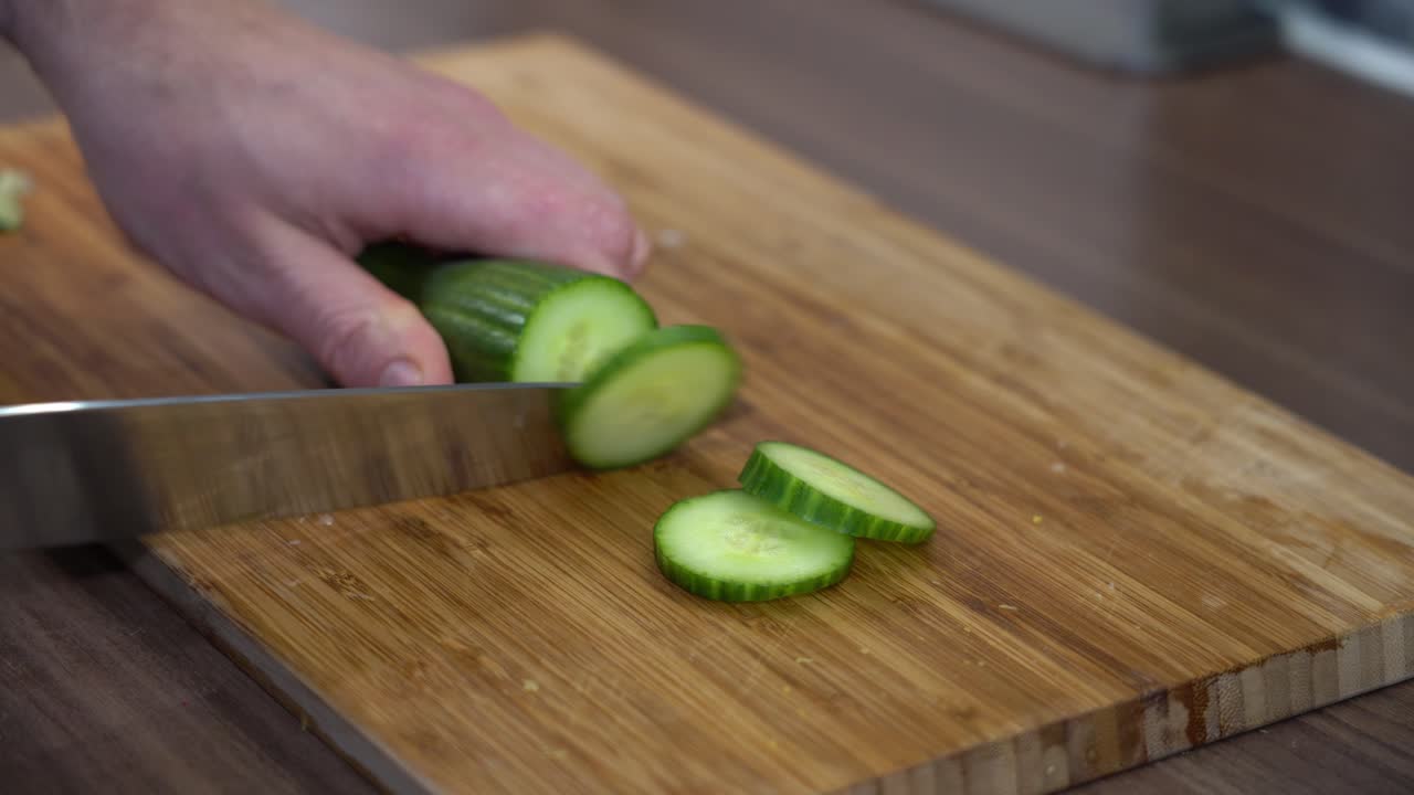 primer plano de un cuchillo rebanado de pepino en contador citchen