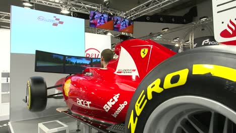 medium shot behind tires of an exclusive mobile and lifelike ferrari at brussels motor show. with a guy gaming in the car.