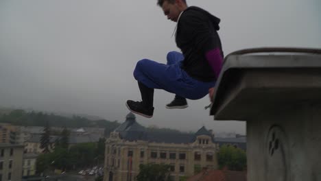 parkour training, jumping off the roof of the staircase on the rooftop of a building in romania - wide shot
