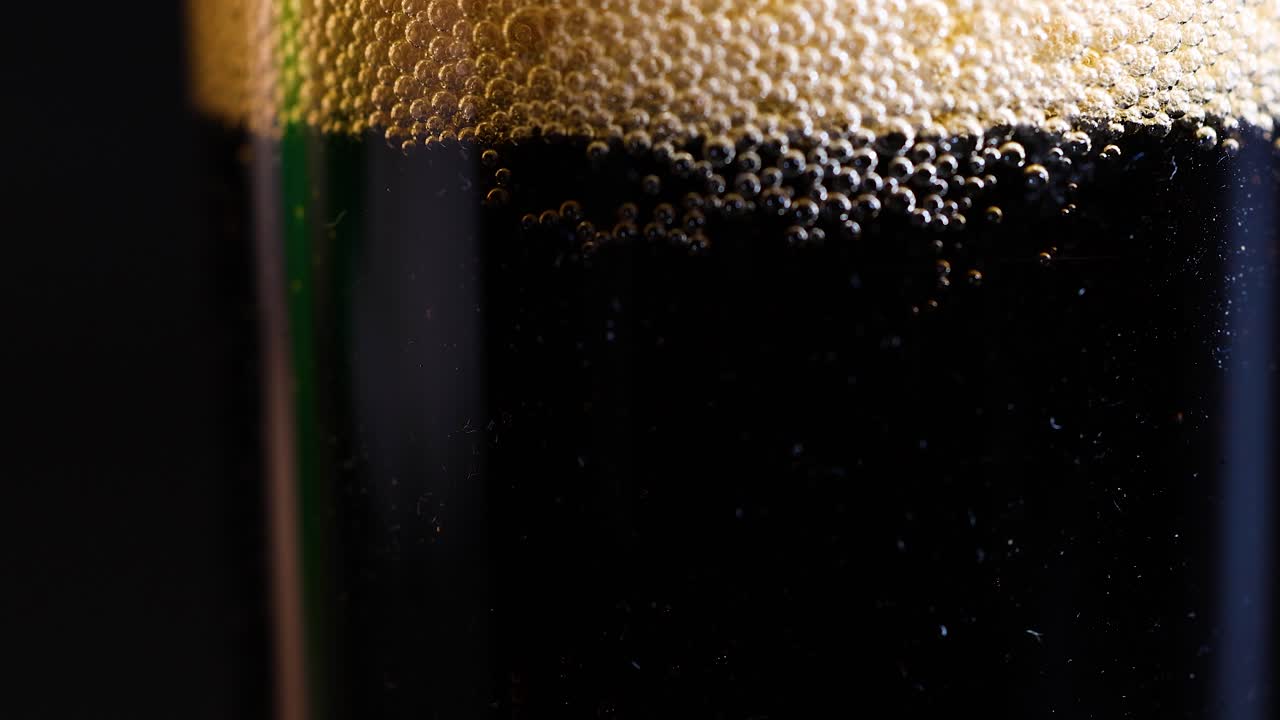 primer plano de un refresco oscuro con burbujas