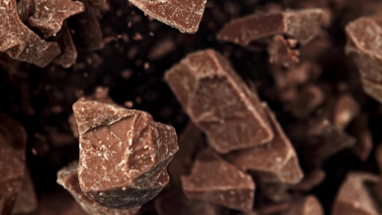 Pezzi di cioccolato che cadono al super rallentatore su uno sfondo scuro