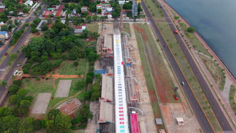 establishing shot above sambadrome and waterfront traffic streets of encarnación city, paraguay, aerial drone view