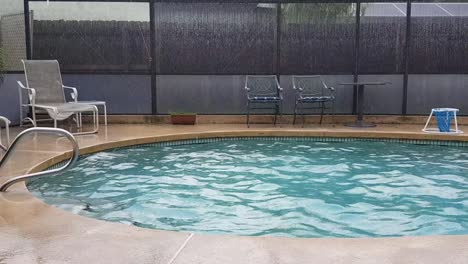 panning view of lounge chairs next to beautiful blue florida home backyard pool during rain, central florida